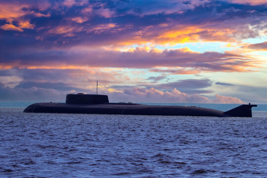 Submarine on the background of beautiful sky. Multicolored clouds over the sea and the submarine. Naval forces concept. Submarine close-up. Military fleet.