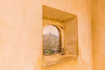 An arch window with a view towards the mountain top fortifications above Jaipur, Rajasthan, India