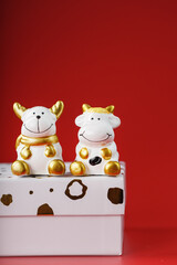 New year's toy of a bull and a cow with a gift on a red background.