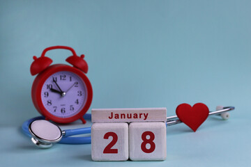 January 28th. White wooden blocks of the calendar with the date, clock and stethoscope on a blue pastel background. Selective focus. health concept