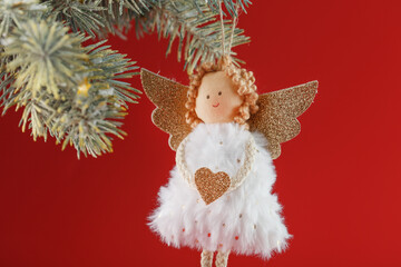White angel toy on a Christmas tree on a red background.