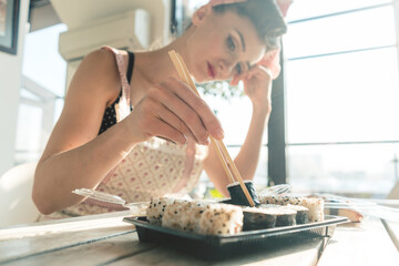 Homemaker woman resting from housework eating some sushi