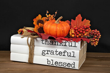 Autumn pumpkin and leaf decorations on stack of books tied with string