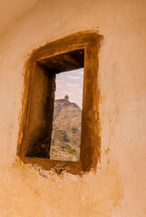 A rectangular window with a view towards the mountain top fortifications above Jaipur, Rajasthan, India