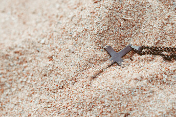 a cross with a chain lies in the sand