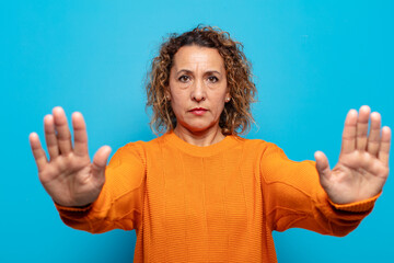 middle age woman looking serious, unhappy, angry and displeased forbidding entry or saying stop...