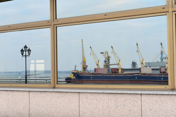 Reflection of the ship and large unloading temples in the glass showcase.