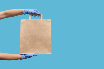 Fototapeta na wymiar Empty paper bag. Shopping bag for groceries. Hands in blue gloves.