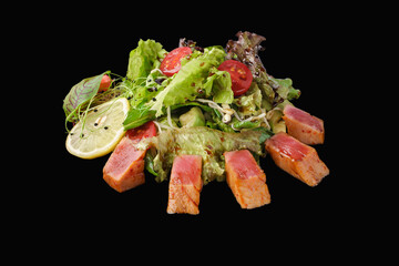 Spicy maguro salad with mix of greens, tuna, cucumber, avocado, cherry tomato, soy sprouts, kimchi sauce, narsharab sauce, lemon, microgreen isolated on black