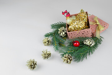 pink box with golden christmas balls, green christmas tree branches and golden cones