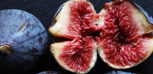 An open fresh red fig and a closed one on slate for food banner