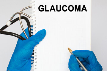 The doctor's blue - gloved hands show the word GLAUCOMA - . a gloved hand on a white background....