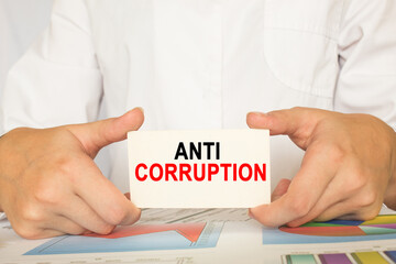 a man in the office holds a card with text ANTI CORRUPTION. business concept