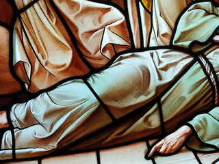 Obraz premium Scene of a body lying on the floor dressed in a robe. Stained glass window detail.