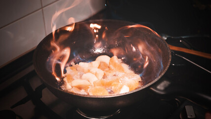 Open fire in a skillet the apple and orange are fried. home kitchen