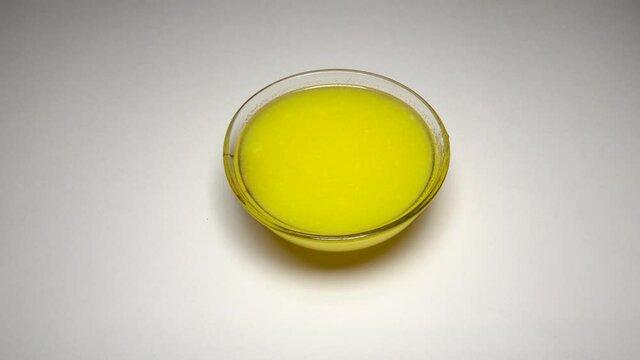 A female hand keeping pure indian ghee bowl on white background.