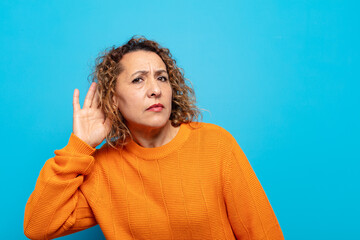 middle age woman looking serious and curious, listening, trying to hear a secret conversation or...