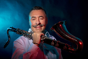 Man with a saxophone in his hands, photo in the studio dark background
