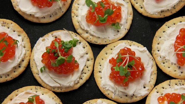 Salmon caviar and soft cheese savory crackers, party food. rotating video