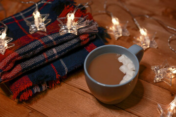 a mug of hot chocolate with marshmallows on the table and lights