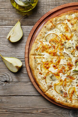 pizza with pear and gorgonzola on a wooden background
