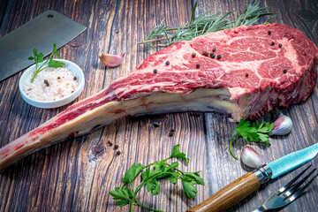 Raw fresh tomahawk steak on wooden background with spices and garlic