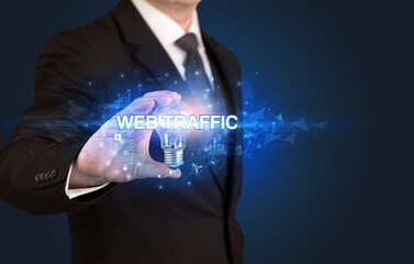 Businessman holding light bulb with WEB TRAFFIC inscription, innovative technology concept