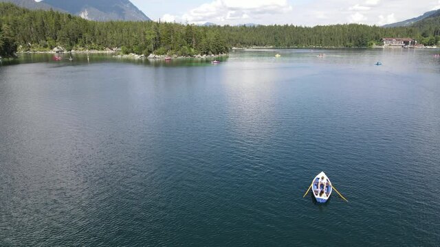 Couple on a rowboat shipping over a lake, Eibsee, aerial drone shot, nature, lovers, vertical jib, movement downwards, Slow Motion