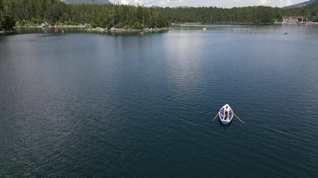 Couple on a rowboat shipping over a lake, Eibsee, aerial drone shot, nature, lovers, vertical jib, movement upwards, Slow Motion