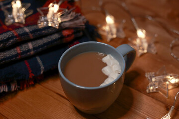 a mug of hot chocolate with marshmallows on the table and lights