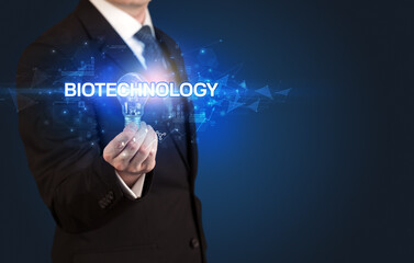 Businessman holding light bulb with BIOTECHNOLOGY inscription, innovative technology concept