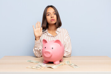 hispanic woman looking serious, stern, displeased and angry showing open palm making stop gesture