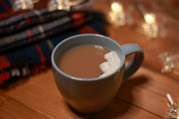 a mug of hot chocolate with marshmallows on the table and lights