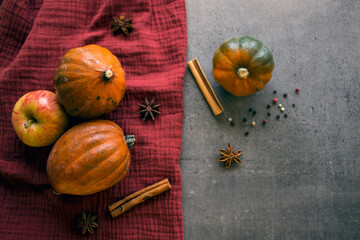 Top view photo of acorn squashes on red textured towel. Gray background with copy space. Seasonal vegetables photo. 