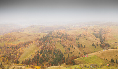 Villages in Romania, aerial view of the authentic places from Rucar-Bran area at the bottom of Bucegi and Piatra Craiului Mountains during an autumn foggy cloudy day with great colors