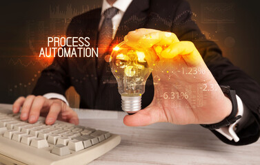 Businessman holding lightbulb with PROCESS AUTOMATION inscription, Business technology concept