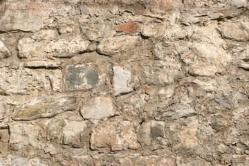 Old beige stone wall texture background close up