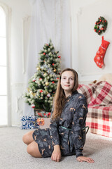 Beautiful teen girl sitting in front of Chrisrmas tree