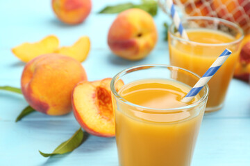Natural peach juice and fresh fruits on light blue wooden table, closeup