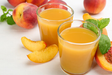 Natural peach juice and fresh fruits on white wooden table, closeup