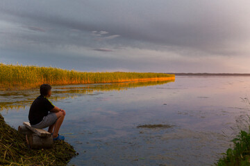 Teenboy sitting and relaxing on lake beach