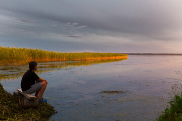 Fototapeta na wymiar Teenboy sitting and relaxing on lake beach