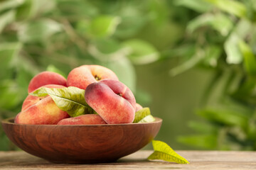 Fresh ripe donut peaches on wooden table against blurred green background. Space for text