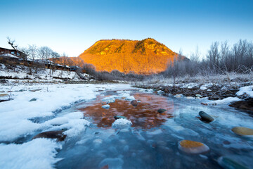 Beautiful sunny winter landscape with ice river and the mountain.