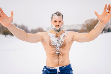Strong brutal naked man with beard in the snow posing outdoors