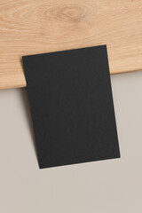 Black invitation card mockup on a beige table. 5x7 ratio, similar to A6, A5.