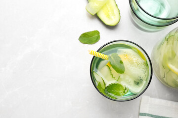 Refreshing water with cucumber, lemon and mint on white table, flat lay. Space for text