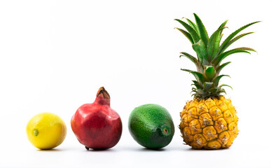 Exotic fruits mix set in one row by size, pineapple, pomegranate, avocado and lemon on white isolated background