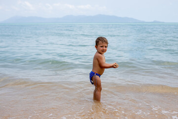 adorable toddler toddler has fun playing on sandy beach of tropical sea
