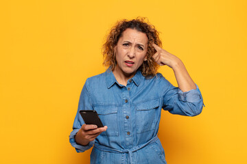 hispanic middle age woman feeling confused and puzzled, showing you are insane, crazy or out of...